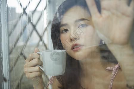 下雨天喝咖啡的年轻女孩图片