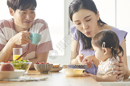 年轻一家人照顾孩子用餐图片