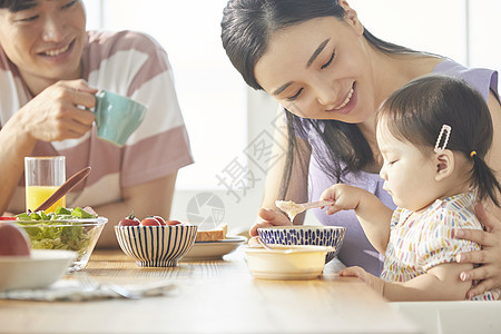 年轻一家人照顾孩子用餐图片