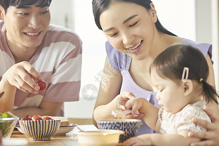 年轻一家人照顾孩子用餐图片