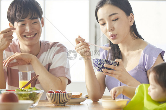 年轻一家人照顾孩子用餐图片