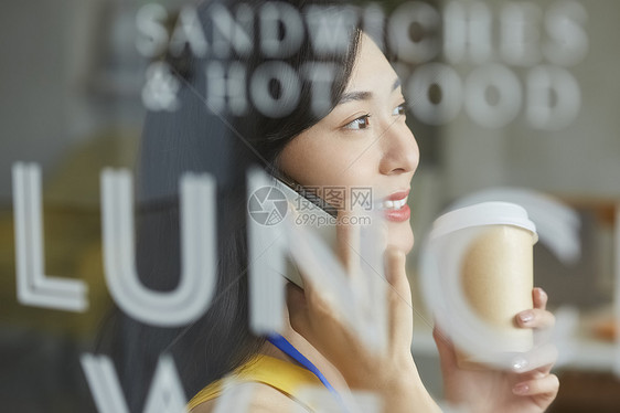 年轻女人拿着咖啡讲电话图片