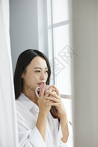 窗口捧着咖啡的年轻女子图片