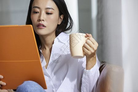 室内青春女人看资料喝茶图片