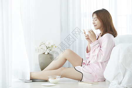 居家女孩靠着床开心喝咖啡图片