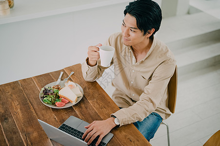 吃饭的男子使用笔记本电脑图片