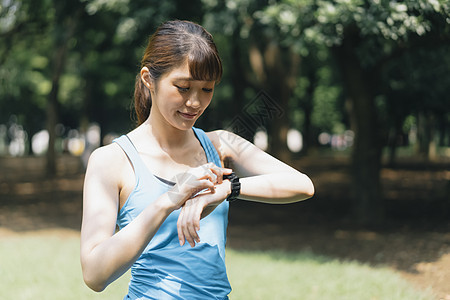 低头看着手表的运动女性图片