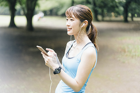 户外拿着手机的运动女青年图片