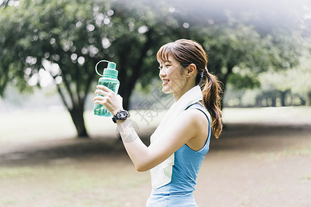 户外拿着水瓶微笑的运动女性图片