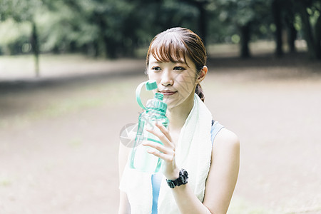 拿着水瓶喝水的青年女子图片