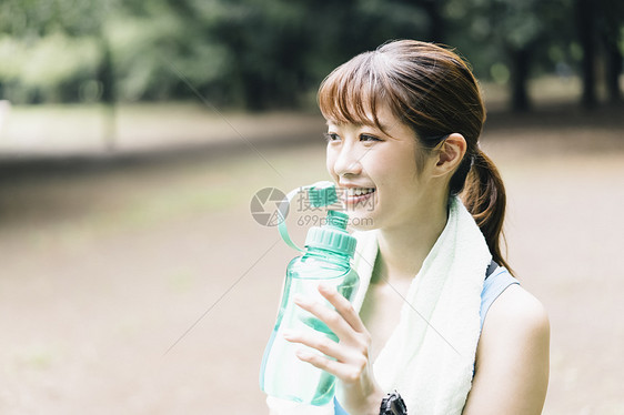 抱着水瓶喝水的女青年图片