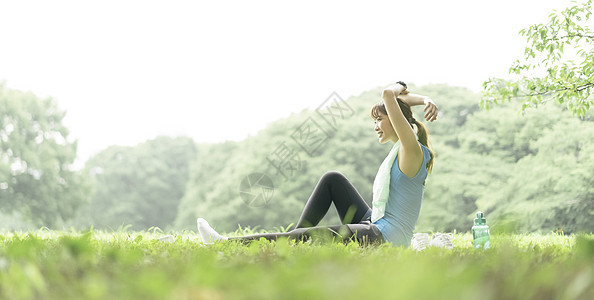 户外草坪上拉伸运动的女青年图片