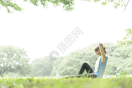 坐在草坪上拉伸的年轻女子图片