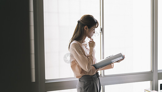 看着文件夹思考的青年女子图片