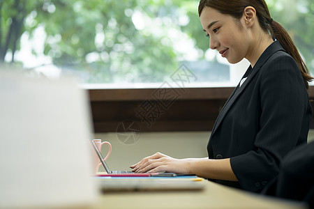 使用笔记本电脑打字工作的女青年图片