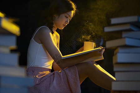 咖啡心情昏黄的灯光下年轻女人在看书阅读背景