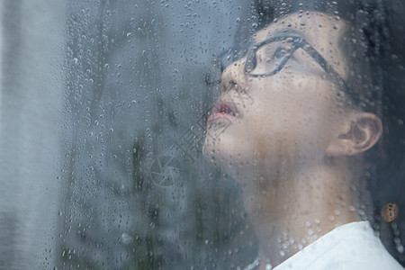 下雨天看向窗外沉思的男青年图片