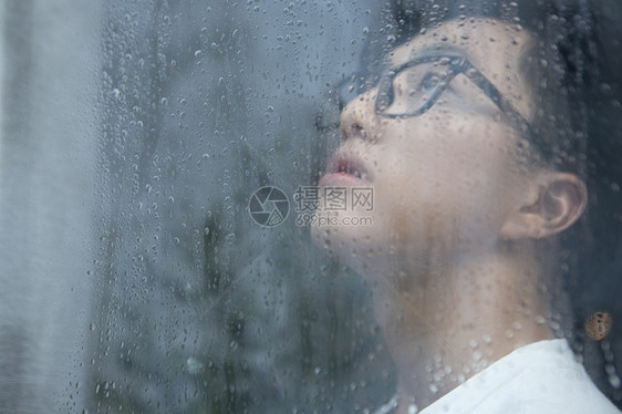 下雨天看向窗外沉思的男青年图片