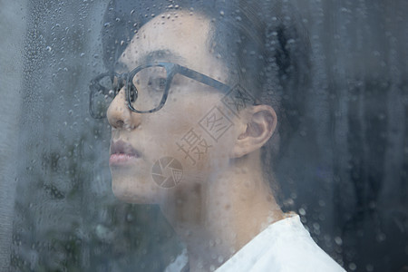 下雨天看向窗外沉思的男青年图片