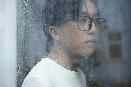 下雨天看向窗外的男青年图片