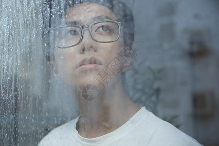 下雨天看向窗外的男青年图片