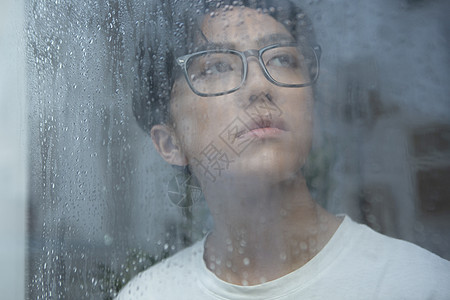 下雨天看向窗外的青年男子图片