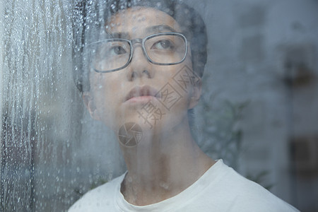 雨天看向窗外的青年男性图片