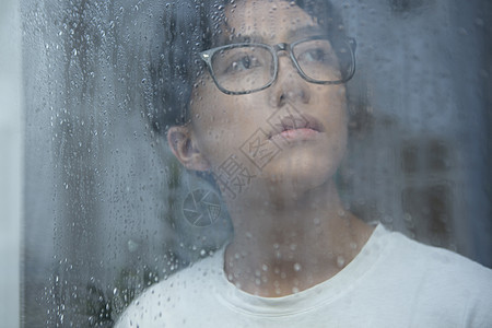 雨天看向窗外思考的青年男性图片