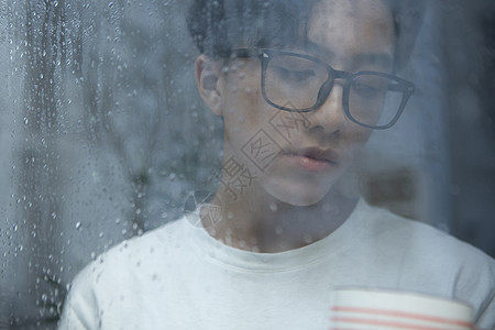 雨天看向窗外的青年男性图片