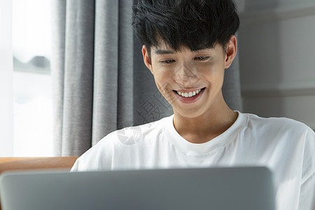 使用笔记本电脑微笑的青年男性图片