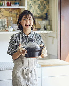 端着锅微笑的年轻女子图片