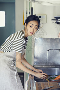 厨房水池洗碗的年轻女子图片