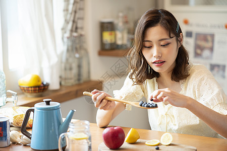 勺子里装满蓝莓的年轻女子图片