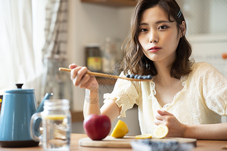 年轻女子手拿装满蓝莓的勺子图片