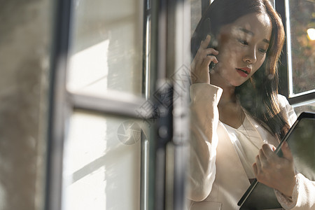 抱着文件接听电话的青年女性背景图片