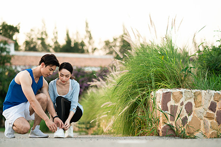 蹲下系鞋带的年轻情侣图片素材