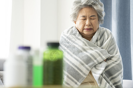 裹着毛毯生病感冒的老年女性图片