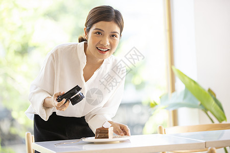 年轻女子拿着相机拍甜品照片图片