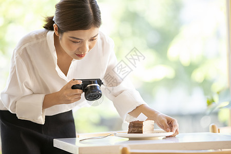 相机拍摄食物照片的年轻女子图片