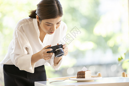 相机拍摄食物照片的年轻女子图片