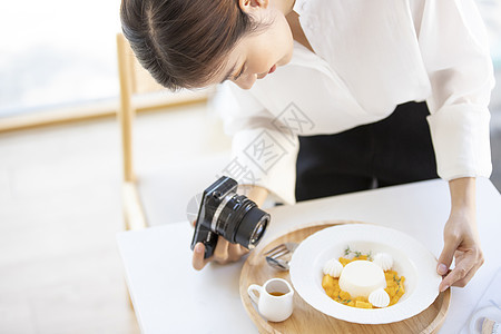 年轻女子拿着相机拍摄食物照片图片