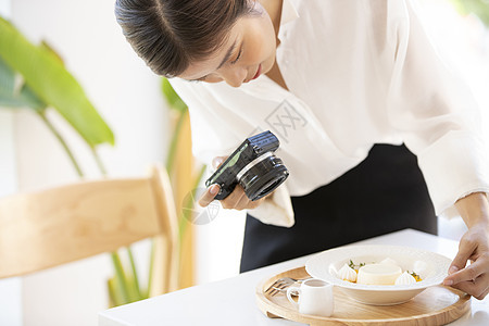 年轻女子拿着相机拍摄食物照片图片