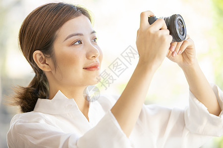 拿着相机拍照的青年女子图片