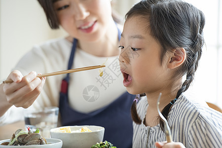 母亲照顾女儿吃饭喂饭背景图片