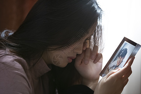 年轻女子看着照片孤独流泪图片