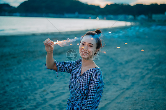 年轻美女海边玩烟花图片