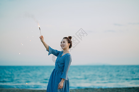 海边放烟花的年轻女子图片