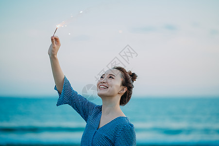 海边放烟花的年轻女子图片