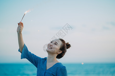 海边放烟花的年轻女子图片