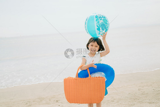 海滩上拿着游泳圈的小女孩图片